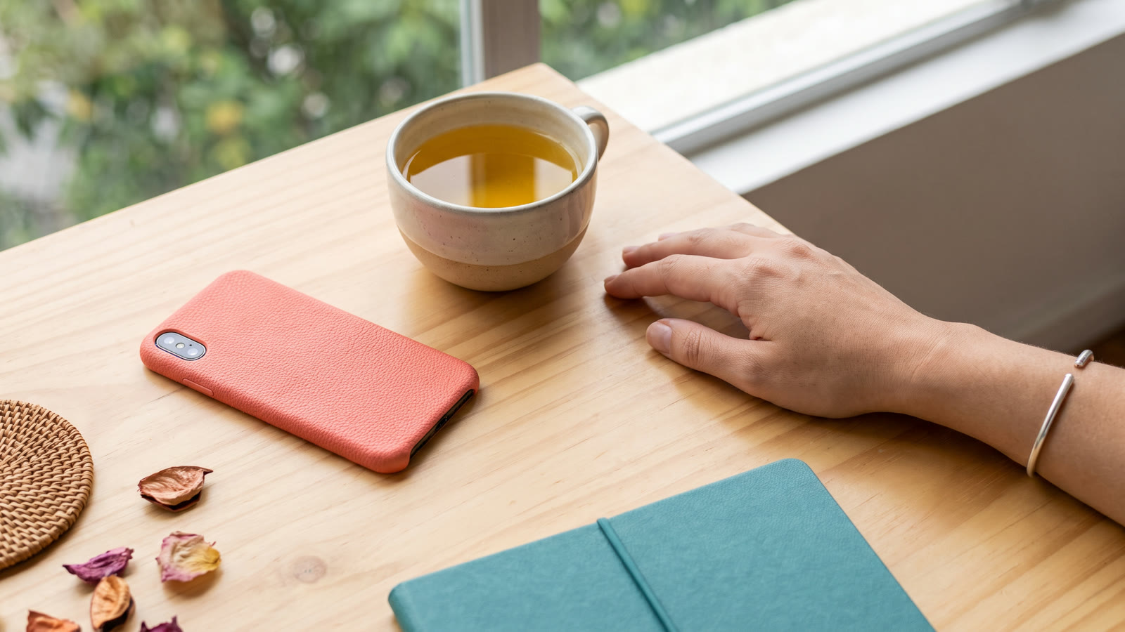 Celular virado para baixo sobre mesa clara ao lado de uma xícara, em luz natural suave